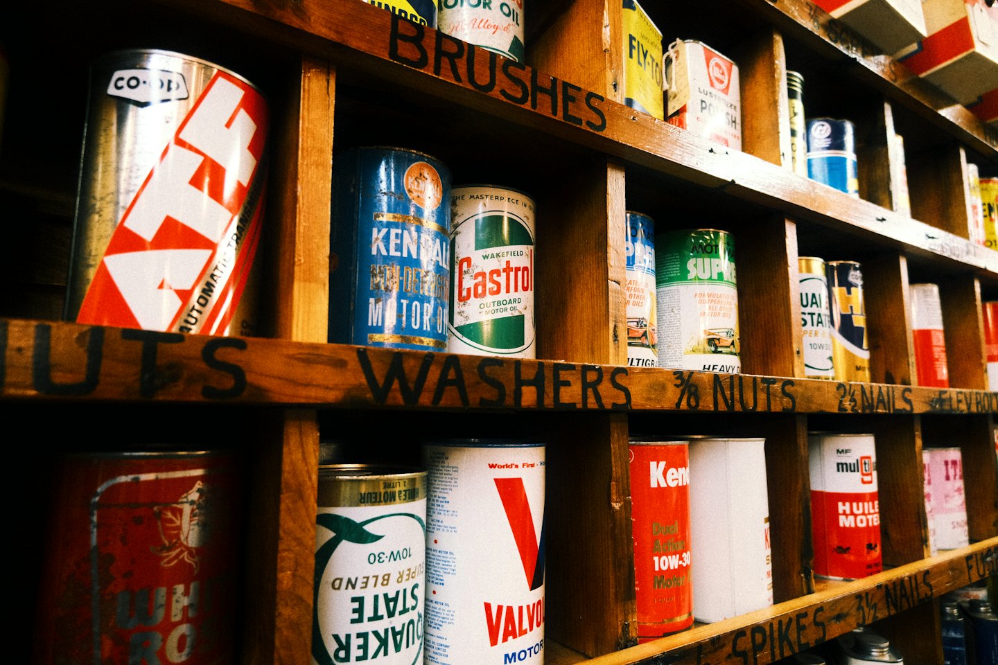 Latas de aceite de motor vintage expuestas en estantes de madera rústica.