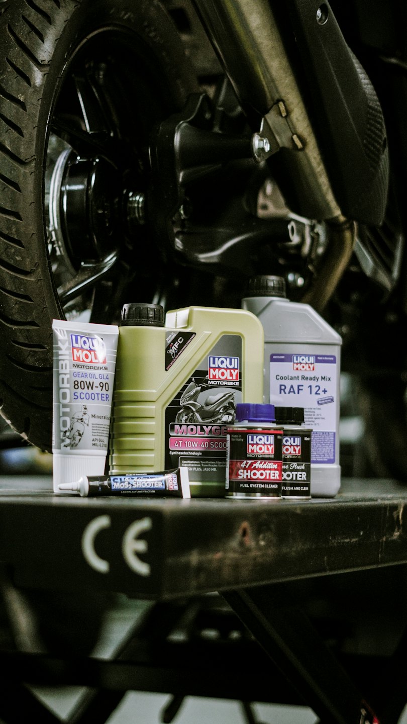 Productos de mantenimiento para motocicletas Liqui Moly dispuestos en un banco de trabajo.