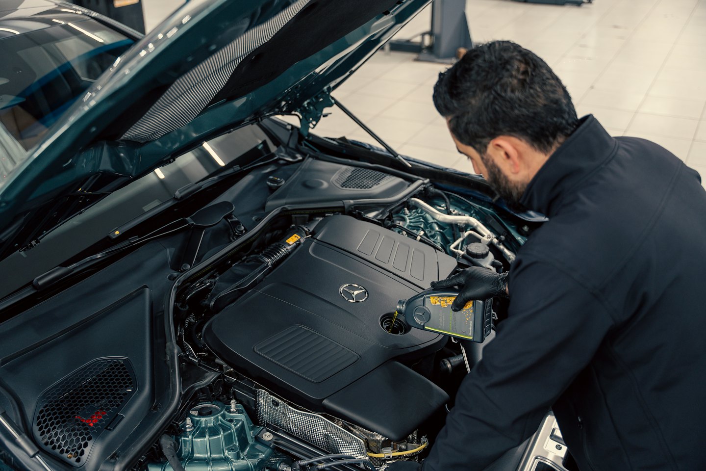 Técnico vierte aceite en el motor de un Mercedes-Benz.